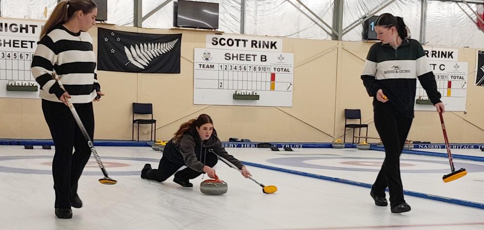 Curler Tahlia Petersen, of Dunedin, (centre) propels a stone down the ice as team-mates Bella...