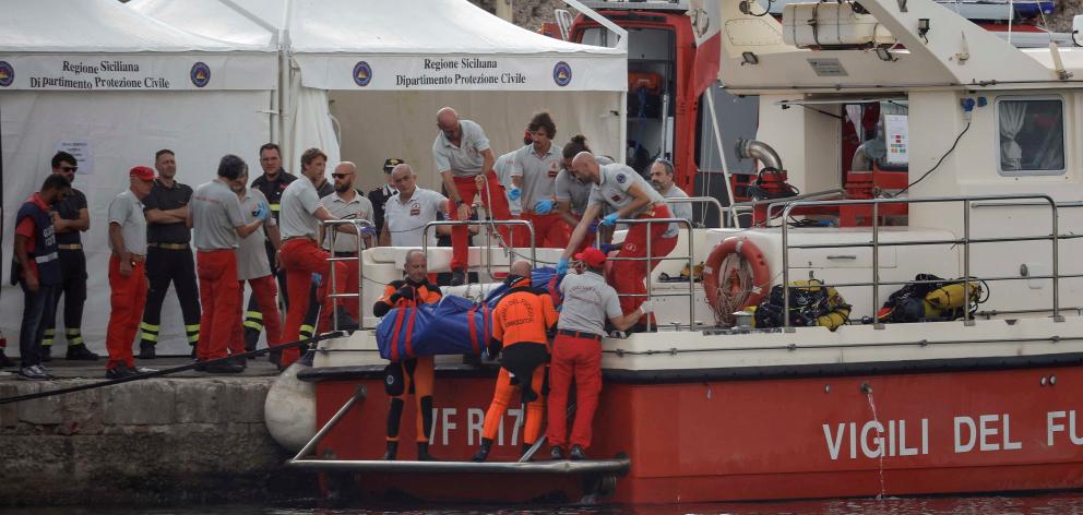 Rescuer lift the a bag containing the body of British entrepreneur Mike Lynch who owned the...