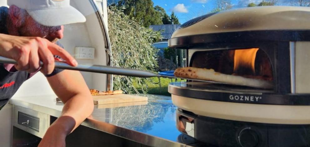 Jon Peneycad takes a pizza out of his gas flame oven. Photo: Supplied