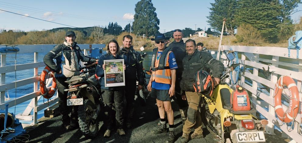 A group of enduro supporters cross the Clutha on the Tuapeka punt, piloted by Tom Jones in high...