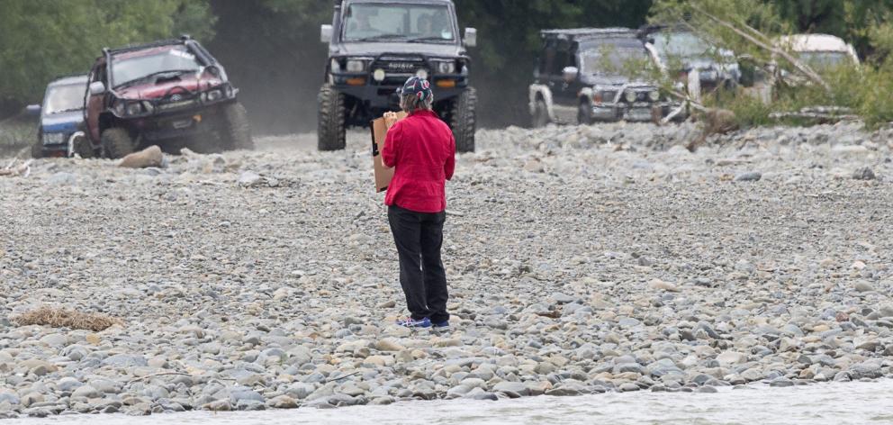 A protester stands in front of a row of 4WD vehicles to try and protect the endangered nesting...