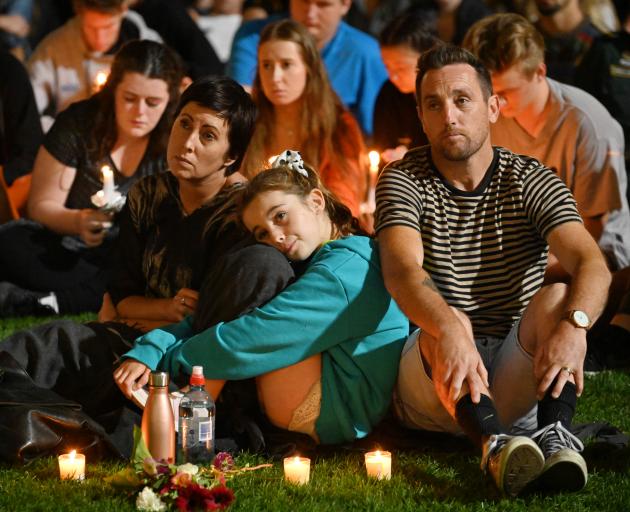 A family burns candles as they listen to the calls for unity, tolerance and respect at last night...