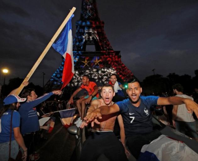 Blue, White, and Red lights and two World Cup stars are projected on the Eiffel Tower after France win the Soccer World Cup final. Photo: Reuters