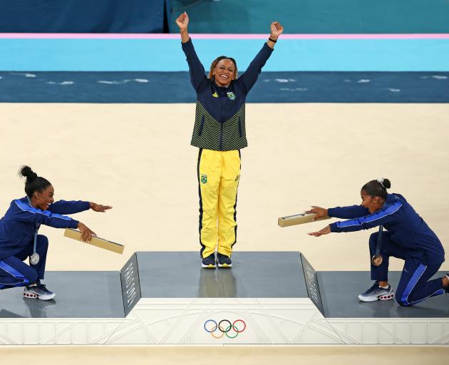 Gold medallist Rebeca Andrade (centre), of Brazil, is bowed down to by silver medallist Simone...