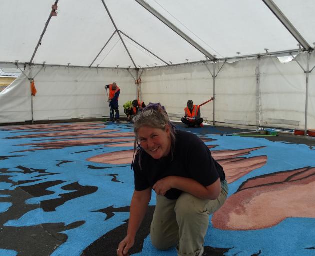 Melbourne artist Jenny McCracken works on the first of two 3-D pedestrian crossings — this one depicting boulders across a river — in Clyde St this week. PHOTO: BRENDA HARWOOD