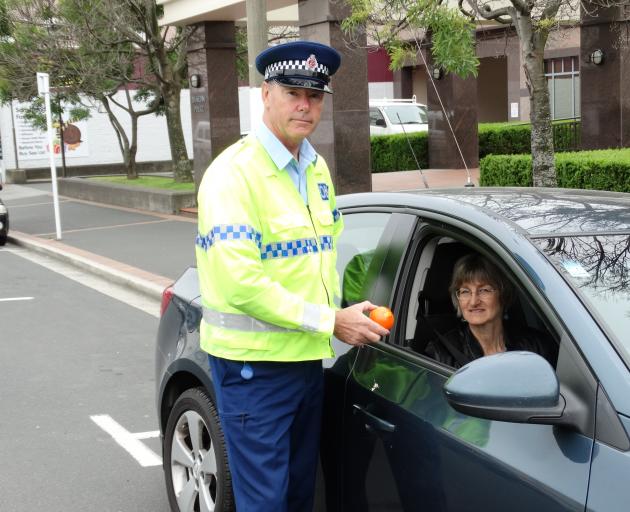 Senior Sergeant Steve Larking passes an orange stress ball to Dunedin City Council road safety...