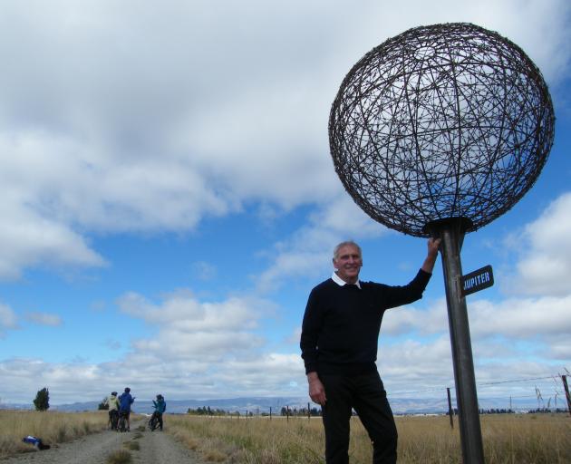 Otago Central Rail Trail operator Graeme Duncan, of Wedderburn, casts his eye over a miniature Jupiter while flanked by cyclists on the rail trail between Ranfurly and Wedderburn. The planet is one of nine in a scale model solar system on the rail trail, 