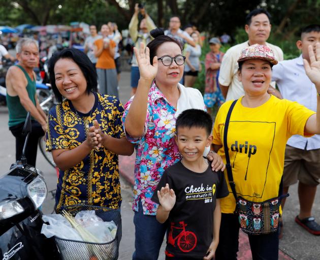 Onlookers wave as an ambulance carrying rescued schoolboys leaves a military airport in Chiang...