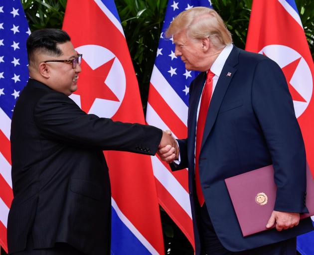 US President Donald Trump and North Korea's leader Kim Jong Un shake hands during the signing of...