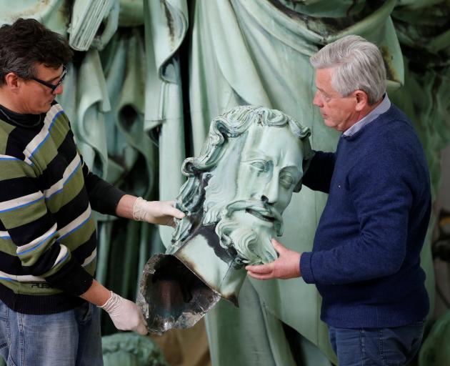 Consultant Patrick Palem (right) checks statues that were removed from the spire of Paris' Notre...