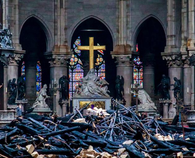 A view of the cross and sculpture of Pieta by Nicolas Coustou in the background of debris inside Notre-Dame de Paris. Photo: Reuters