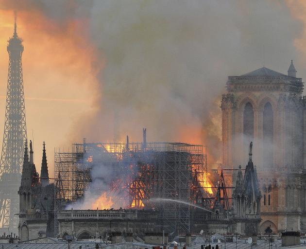 Flames and smoke rise from the blaze after the spire toppled over on Notre Dame cathedral in...