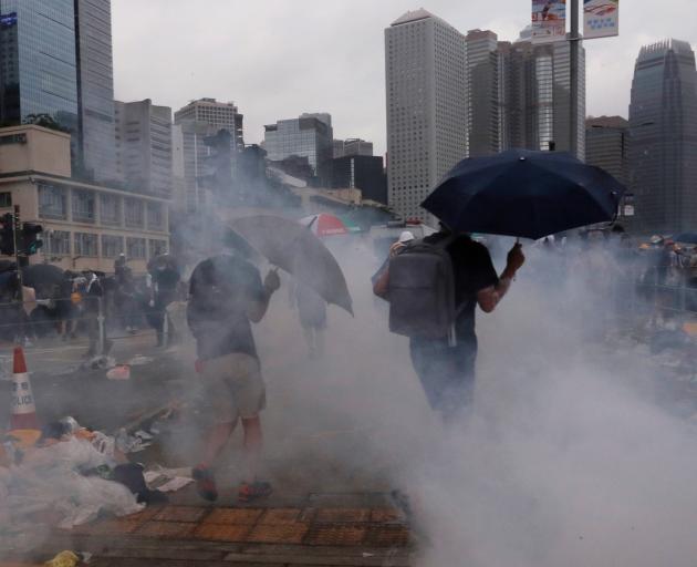 Protesters react to tear gas during a demonstration against a proposed extradition bill in Hong...