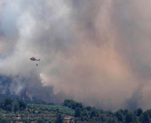 A helicopter drops water over a fire during a forest fire near Bovera, near Tarragona in Spain. Photo: Reuters