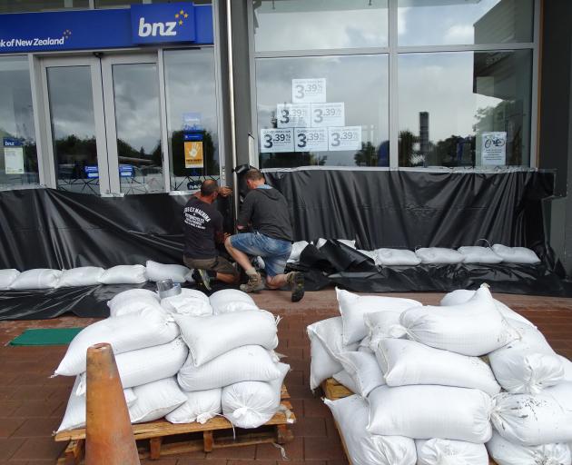 Jarvie Plumbers flood proofing the Wanaka BNZ branch yesterday afternoon ahead of a potential flood this morning. Photo: Kerrie Waterworth