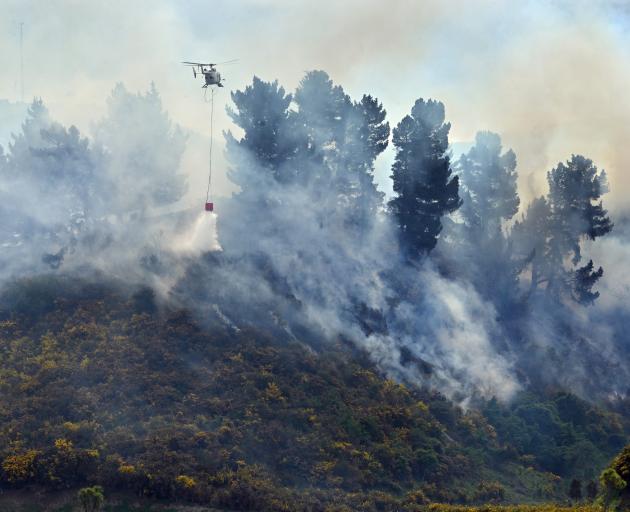 A helicopter drops water on to a gorse fire off State Highway 1, near Waikouaiti, yesterday....