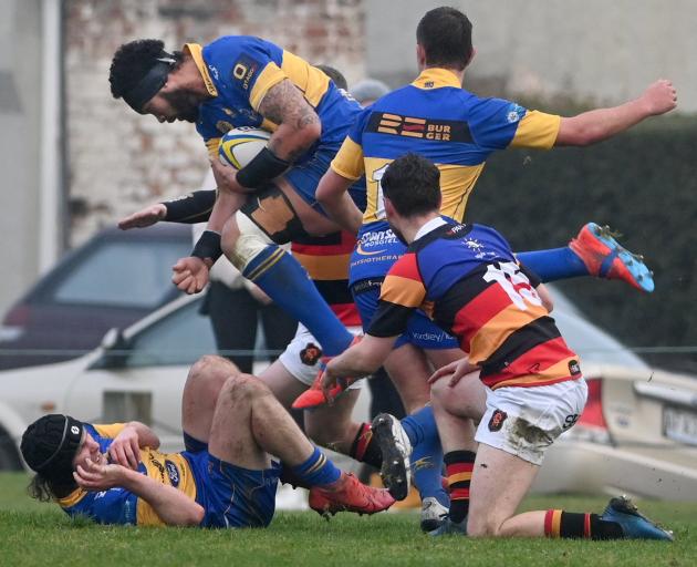 Taieri lock Don Lolo carries the ball in traffic as teammates Mark Rooney (on ground) and Brayden...