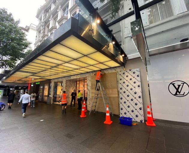 Workers replace the glass in front of the Gucci store in Queen St, which was targeted in a ram raid overnight. Photo: Craig Kapitan