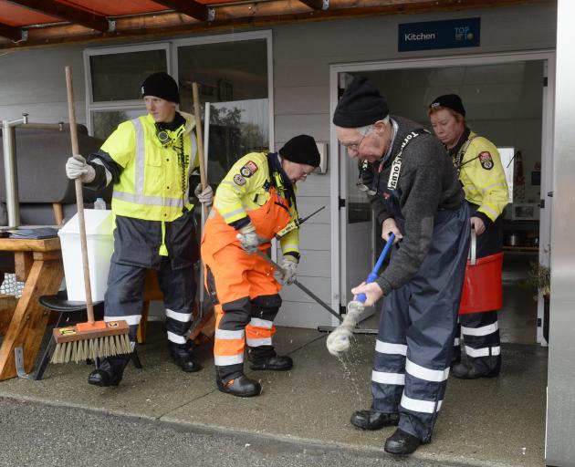 Omarama Volunteer Fire Brigade station officer Maurice Cowie wrings out his mop while (from left)...