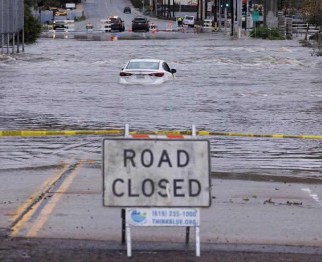 An abandoned car sits trapped on the street in overflow water from the San Diego River in San...