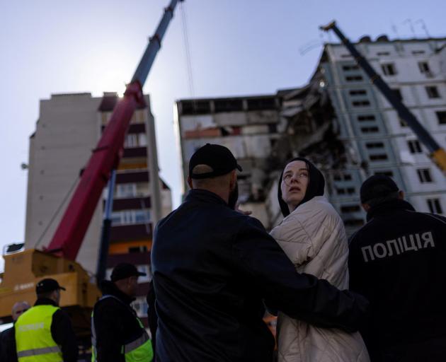 Residents and emergency workers near the site of a heavily damaged residential building hit by a...