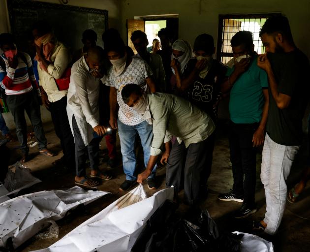 People try to identify the bodies of victims of a train collision, as they lie in a school that...