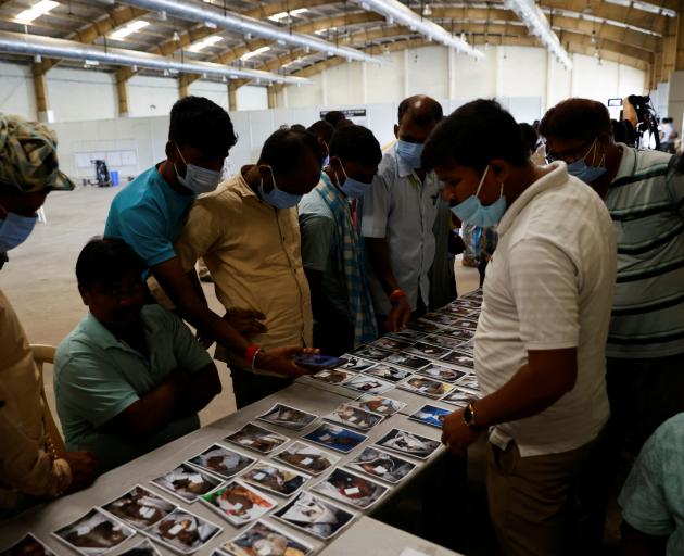 People look at pictures to identify the bodies of victims of a train collision, at a temporary...