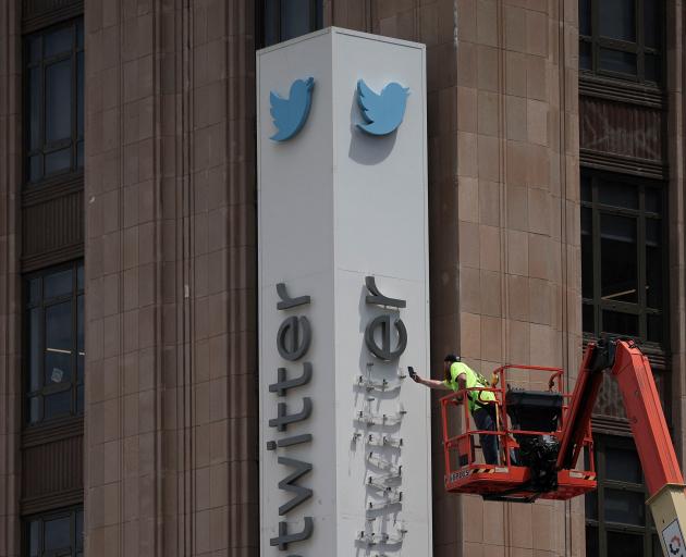 A worker dismantles Twitter's sign at the social media company's corporate headquarters in San...
