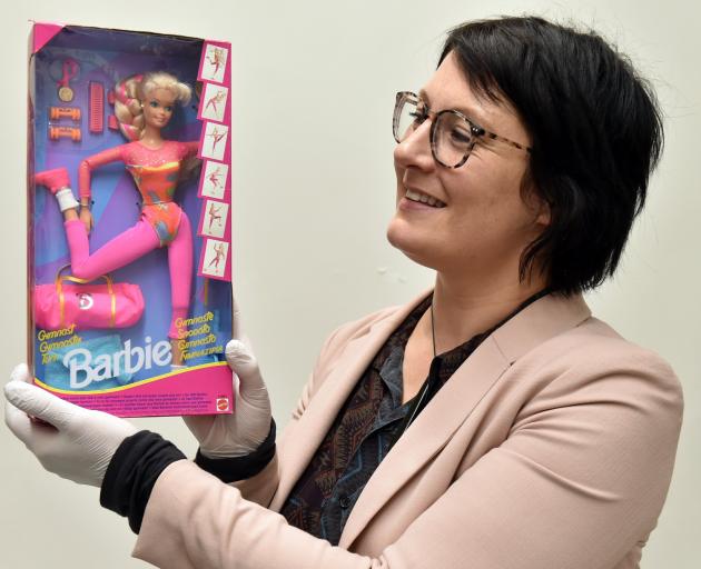 Otago Museum humanities collection manager Anne Harlow shows off a gymnast Barbie from 1993....