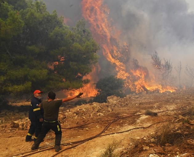 Locals help firefighters as they try to extinguish a wildfire burning near the village Vlyhada...