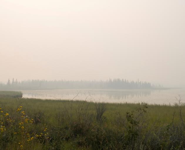  A lake outside Yellowknife is covered in smoke after a state of emergency was declared due to...