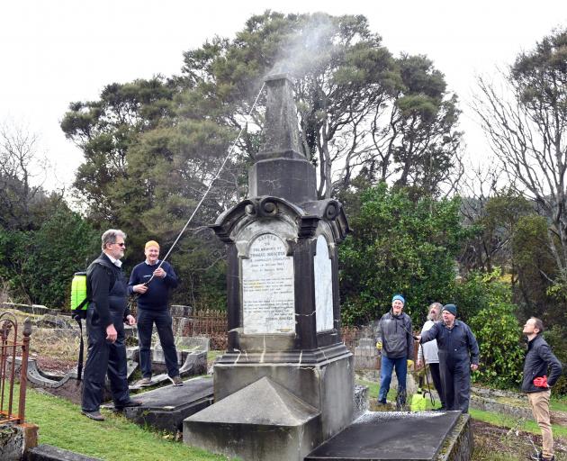 Cleaning Thomas Bracken’s tombstone in the Dunedin Northern Cemetery on Saturday are (from left)...