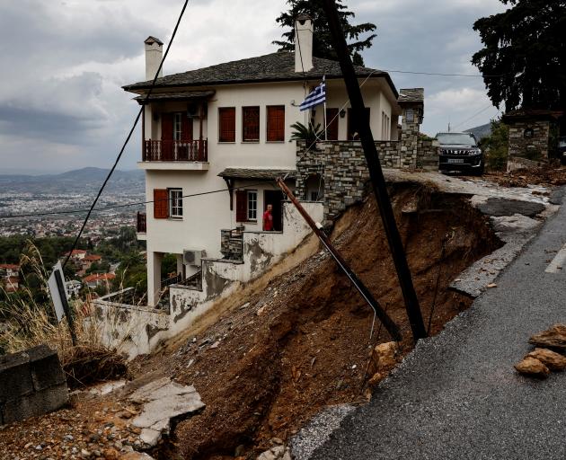 A man stands in a house near a collapsed road after torrential rains destroyed the infrastructure...