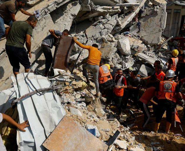 Palestinians search for casualties at the site of an Israeli strike on a house in Khan Younis, in...