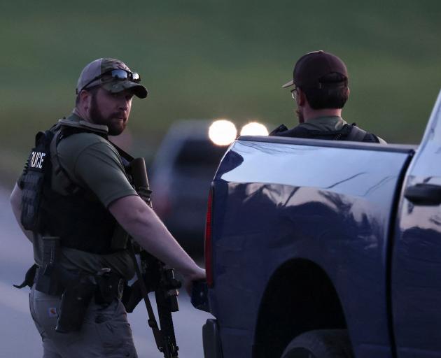 Law enforcement members search for a suspect, following a deadly mass shooting in Lewiston, in...