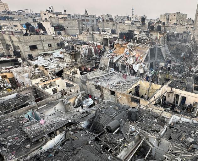 People search through the rubble of damaged buildings following an Israeli air strike on...