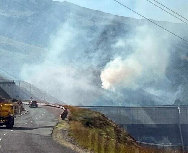 Crews work to keep a fire away from power lines over the Clyde Dam on Saturday. PHOTOS: FIRE AND...