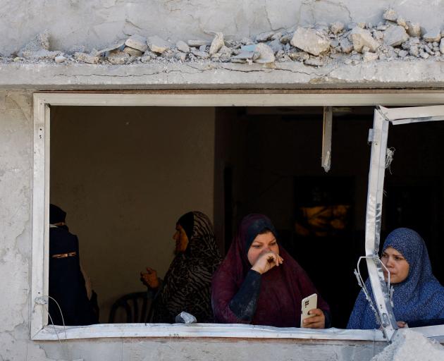 Palestinians look on at the site of an Israeli strike on a house in Rafah, in the southern Gaza...