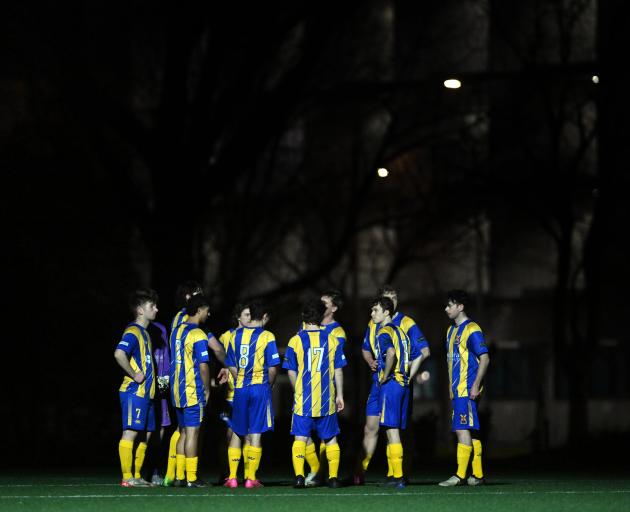 Otago University footballers huddle in the dark. 