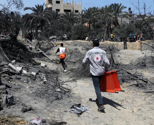 Emergency workers rush to attend to victims after an Israeli air strike on the Al-Mawasi camp for...