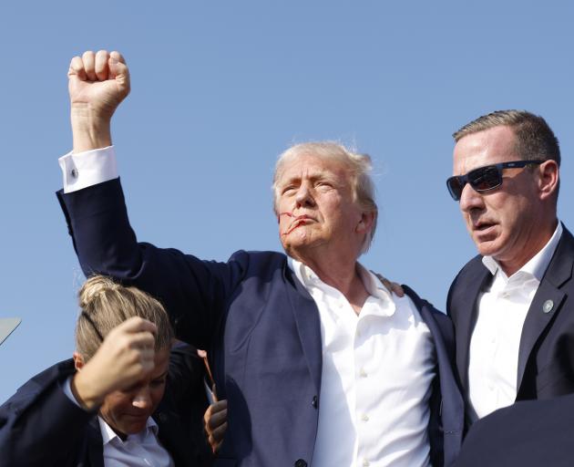 Donald Trump raised a fist to the crowd as he was escorted from the stage by the Secret Service....