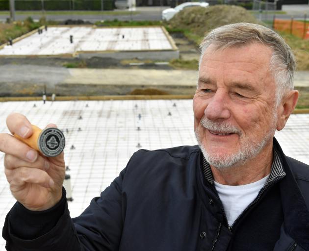 Roger Fewtrell displays the stamp of his new housing charity in front of two houses he is...