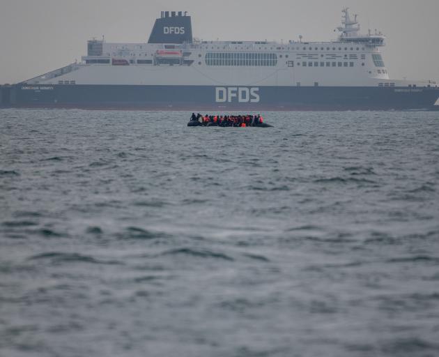 An inflatable dinghy carrying migrants passes a passenger ferry in the English Channel. PHOTO:...