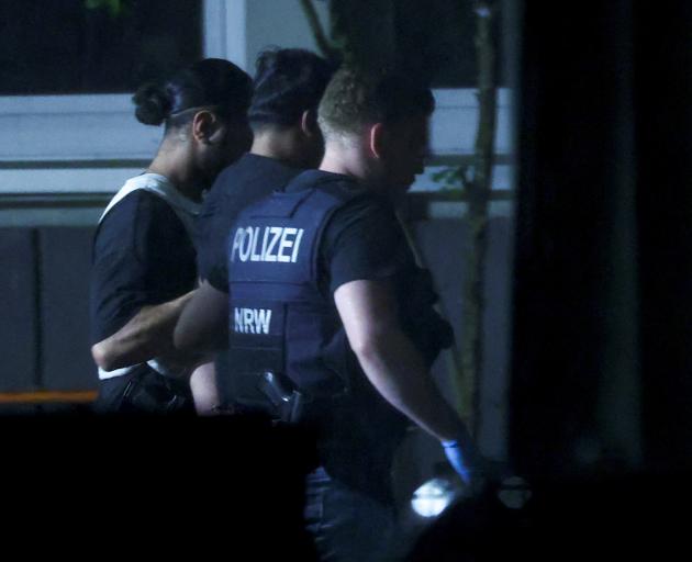 Police officers detain a person, following an incident in which several individuals were killed...