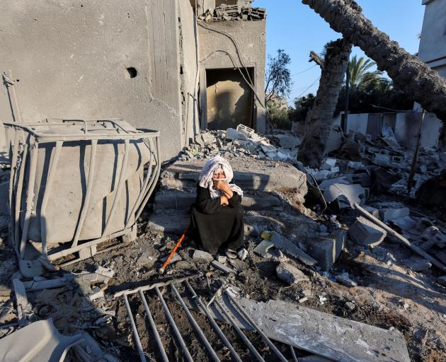 A Palestinian woman sits at the site of an Israeli strike on a house in Deir Al-Balah in the...