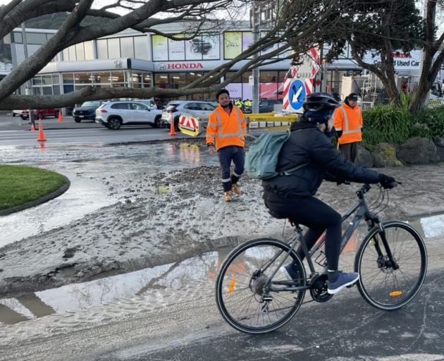 Cyclists ride through layers of silt as contractors put traffic management in place on Wednesday....