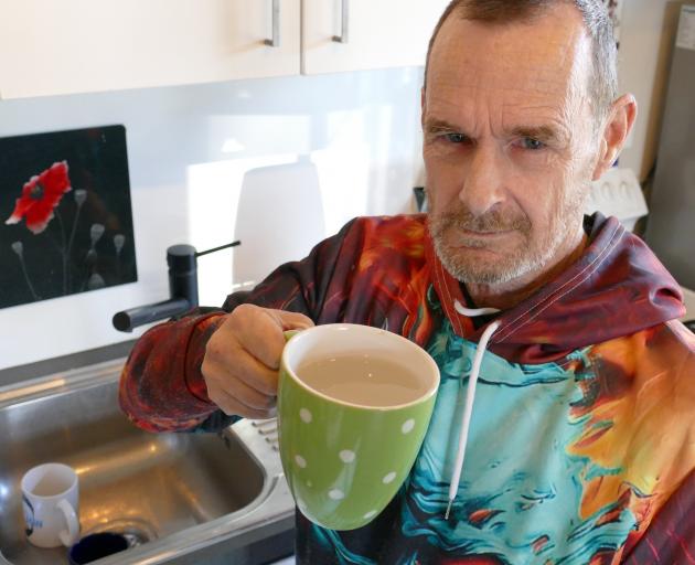 Milton resident Graham Button holds a mug of the tap water he believes may have caused a serious...