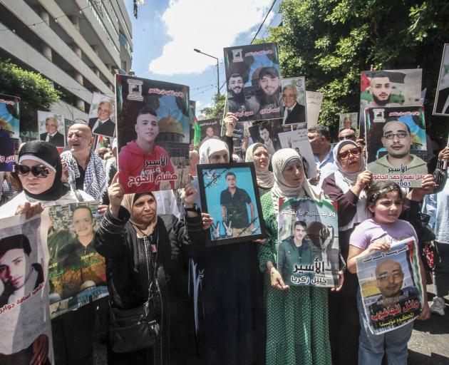 Demonstrators wave flags and hold pictures of Ismail Haniyeh during a protest over his death in...