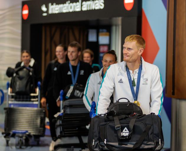 Finn Butcher is followed by Lisa Carrington and other New Zealand Olympians as they arrive at...