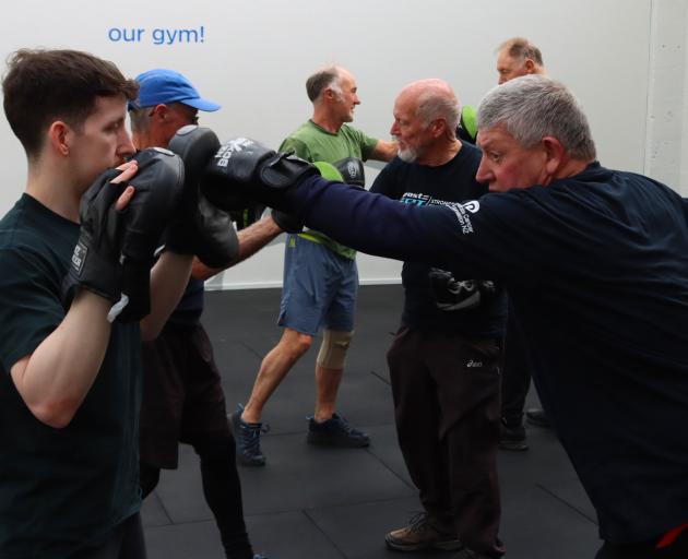 NRG personal trainer Jake Kelly (left) holds punching mitts while Prost-Fit member Andrew Brown...